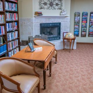 A cozy library corner with bookshelves, a fireplace, and comfortable seating.