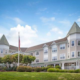 A picturesque building with peaked roofs and a landscaped front lawn under a bright blue sky.