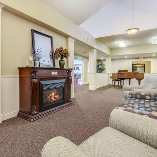 A cozy living room featuring a fireplace, grand piano, and comfortable seating.
