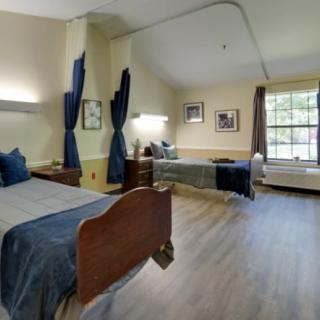 A cozy bedroom with two beds, elegant furnishings, and natural light from a large window.