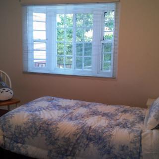 A cozy bedroom with a single bed and a window overlooking greenery.
