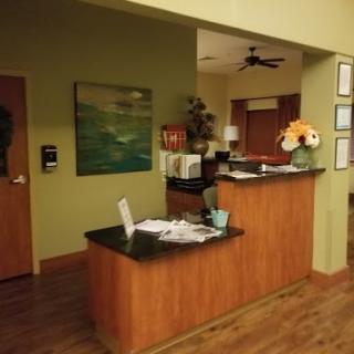 A cozy reception area with wooden furniture and a green wall, featuring a welcoming atmosphere.