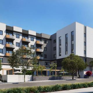 A modern apartment building featuring multiple balconies and surrounded by trees.