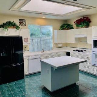 Modern kitchen with a central island, skylight, and green tile flooring.