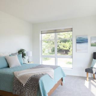 A bright and modern bedroom with minimalist decor, featuring a comfortable bed and large window.