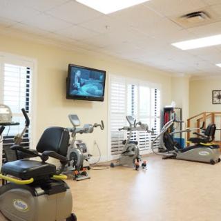 A well-equipped fitness center featuring various exercise machines and a television for entertainment.