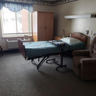 A spacious hospital room equipped with a patient bed and a comfortable chair, featuring a window that lets in natural light.