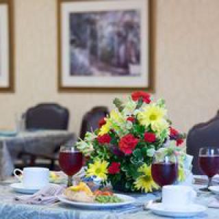 A beautifully set dining table with a colorful floral centerpiece and plates of food.