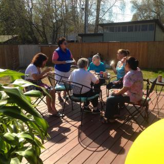 A group of people enjoying a sunny gathering on a wooden deck.