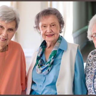 A group of elderly women smiling together indoors.