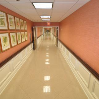 A long, well-lit hallway with framed art on the walls and clean tile flooring.