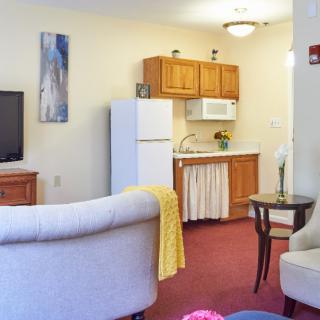 A cozy living space with a small kitchen area, featuring a refrigerator and microwave.