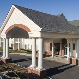 A building entrance featuring classical columns and a peaked roof.
