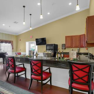 A modern bar area with high chairs and pendant lighting.