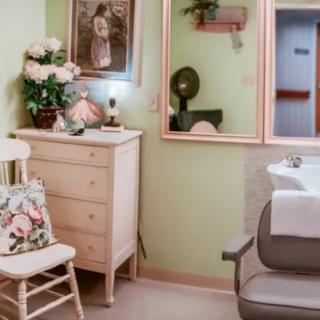 A vintage-style room with a salon chair, dresser, and floral accents.