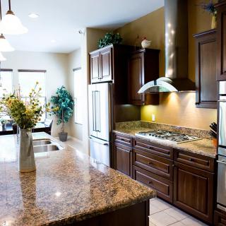 A modern kitchen features granite countertops, wooden cabinets, and stainless steel appliances.
