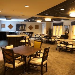 An empty dining area with neatly arranged tables and chairs, featuring warm lighting.