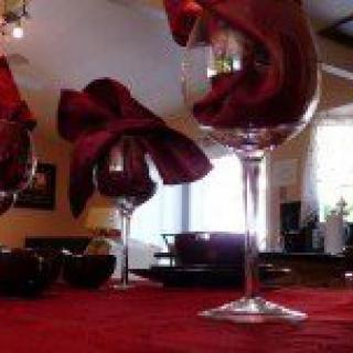 An elegant table setting featuring wine glasses with red napkins, set in a warmly lit dining room.