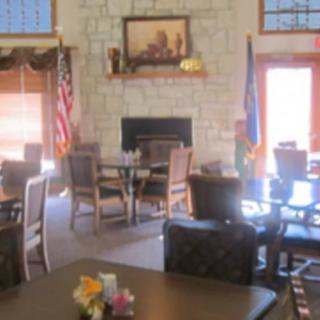 A cozy dining area with a stone fireplace, wooden chairs, and decorative flags.