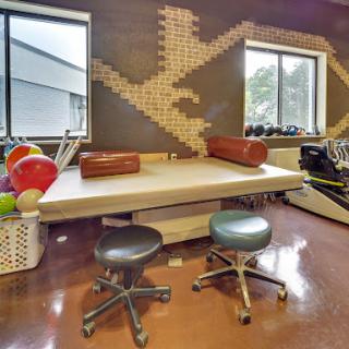 A well-equipped physical therapy room featuring a therapy table, exercise balls, and sleek seating arrangements.