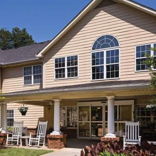 A charming two-story residential building with a welcoming porch and outdoor seating.