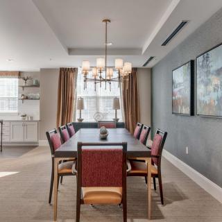 A modern dining room with a large table, elegant chairs, and a stylish chandelier.