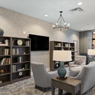 A cozy living room with bookshelves, comfortable seating, and a modern chandelier.