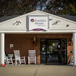 The entrance to Franklin Woods, a welcoming community center adorned with rocking chairs.