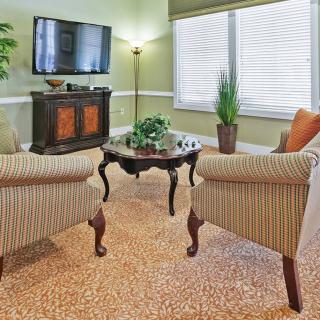 A cozy living room with striped chairs, a wooden coffee table, and a television mounted on the wall.