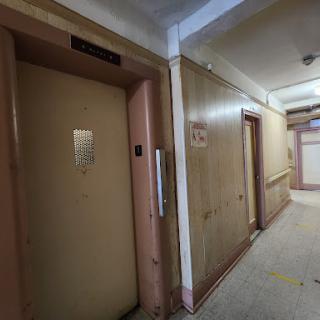 A view of an elevator and hallway in a vintage building.