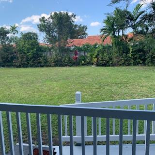 A backyard view with a grassy lawn and surrounding trees, seen from a deck.