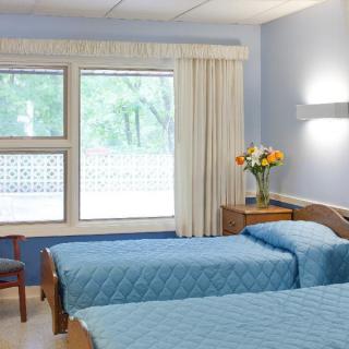 A bright hospital room with twin beds and blue decor.