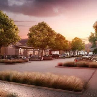 A serene urban street illuminated by a warm sunset, lined with trees and parked cars.