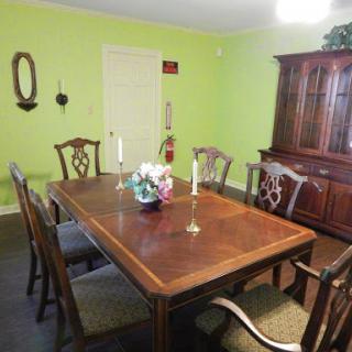 A cozy dining room featuring a wooden table and chairs, accented by green walls and a beautiful floral centerpiece.