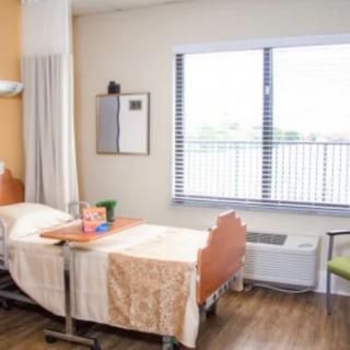 A hospital room with a neatly arranged bed and a window letting in natural light.