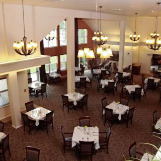 An elegant and spacious dining area with neatly arranged tables and decorative chandeliers.