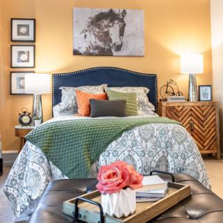 A cozy bedroom with a beautifully decorated bed, bedside lamps, and artwork on the wall, creating a warm and inviting atmosphere.