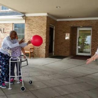 A joyful group of elderly individuals engaging in an outdoor balloon activity.