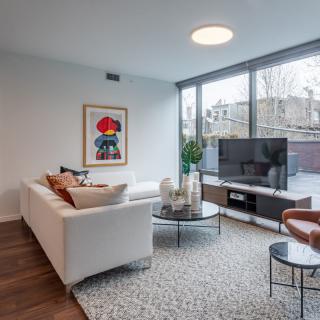 A modern living room with a white sofa, colorful artwork, and a large flat-screen TV.