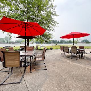 A charming outdoor patio featuring red umbrellas, perfect for enjoying a meal amidst nature.
