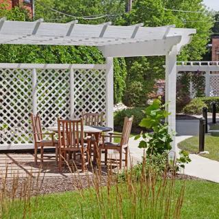 A cozy outdoor seating area with a wooden pergola surrounded by lush greenery.
