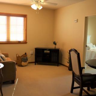 A cozy living room with a sofa, dining table, and a window with blinds.