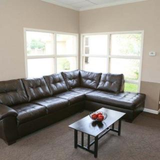 A cozy living room with a large sectional sofa and a small coffee table, illuminated by natural light through multiple windows.