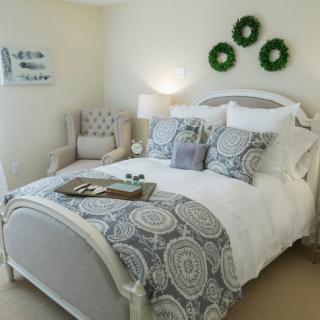 A cozy and elegantly decorated bedroom with a comfortable bed, pillows, and a side chair.