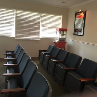 A cozy waiting room featuring a row of chairs, a popcorn machine, and decorative posters on the wall.