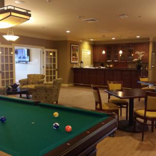 A cozy lounge area featuring a pool table and bar with comfortable seating.