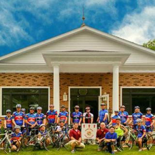 A group of cyclists posing in front of a building.