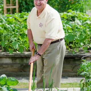 A man gardening outdoors with a garden tool.
