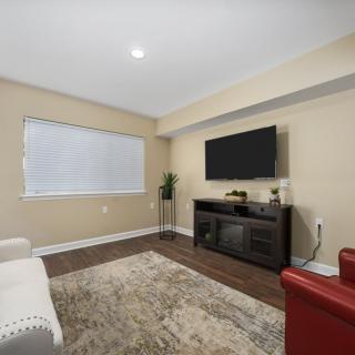 A modern living room with a flat-screen TV, couch, and wooden flooring.