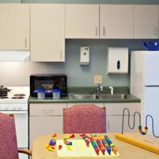A kitchen play area with toys on the table and cabinets in the background.